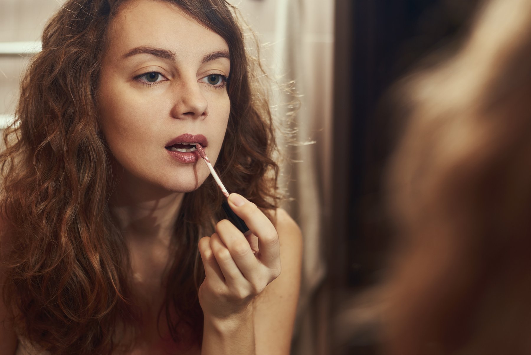 Woman Applying Make up in Front of Mirror